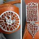 Left a reproduction tinned baldric phalera with the word OPTIME MAXIME CON(SERVA) in openwork around an eagle with wings stooped and head turned to right; on the right a rectangular baldric plate with the openwork words NUMERUM OMNIUM (with Us as Vs) and, hinged to it, a heart-shaped pendant with the word MILITANTIUM, both tinned. Motto means something like 'Best and Greatest, protect the whole unit in service'. Image: MCB Tinned openwork baldric fittings consisting of a phalera and a hinged terminal plate and pendant.