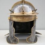 Replica ferrous Niederbieber-type helmet with copper-alloy edging, brow band, brow guard, ear guards, and cross-pieces. 3rd century. Image: Einsamer Schütze Front view of a ferrous Niderbieber-type helmet with brass fittings.