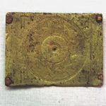 Copper-alloy belt plate with chased and punctim decoration, the central boss being surrounded by a hunt scene. Image MCB Brass-coloured belt plate.