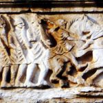 Frize from the Augustan arch at Susa depicting Roman soldiers with oval shields and helmets. Image: Zairon Troops pass from left two right, including (from left to right) a dismounted horsmen, three legionaries, a mounted cavalryman, and a fleeing enemy horseman.