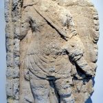 Fragmentary tombstone found in Trier in 1888. It depicts a soldier holding two spears in his right hand and (apparently) the scabbard of a sword in his left. His tunic has the characteristic hem and folds of a pre-Flavian tombstone. He also appears to be wearing a <i>sagum</i> and a baldric over his right shoulder. A belt and apron can be made out. Image: MCB (CC BY-SA 2.0) Damaged infantry tombstone of an unknown soldier, missing the neck upwards and the shins downwards.