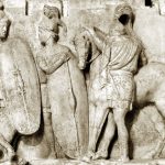 Portion of the so-called Altar of Domitius Ahenobarbus depicting two legionaries (with large, curved, oval shields with spinae and 'barleycorn' bosses, mail body armour, and crested helmets) and a mail-clad and helmeted cavalryman. Image: jastrow (PD) Two legionaries with large oval shields converse whilst a cavalryman deals with his mount.