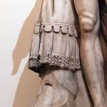 Detail of a front view of the Ludovisi Antoninus Pius statue showing a draped garment with lappets and pteryges, identified by Robinson as an arming doublet. Image: MumblerJamie (CC BY-SA 2.0) Depiction in marble of a garment draped over a tree stump with a Corinthian helmet at its base.