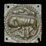 Copper-alloy lupercal-type embossed belt plate from Oberstimm (DEU).There are four rivets holes, one in each corner, for attaching it to the leather belt. Image: Archäologische Staatssammlung München (CC BY-NC-ND 4.0) Square embossed belt plate depicting the wolf and twins with a rivet hole in each of the four corners. It retains a shiny green patination.