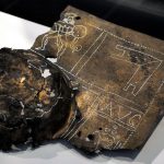 Fragmentary curved, rectangular, copper-alloy shield boss similar to the example from the River Tyne. Found at Vindonissa. Image: DerHexer (CC BY-SA 4.0) Top right corner and part of the dome of a shield boss from a legionary shield, decorated with incised lines and punched dots picked out in white.