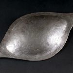 Oval ferrous shield boss found (together with the remains of shield edging) on the Hunerberg at Nijmegen (NLD). Image: Museum het Valkhof (Public Domain Mark 1.0) Oval ferrous shield boss with two rivets on the expanded flange on the narrow ends with a shiny patina.